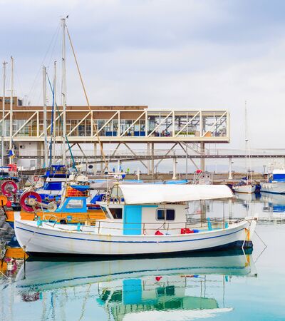 Limassol city harbor view, moored fishing motor boats, restaurants on the pier under heavy sky with rainy clouds, Cyprusの写真素材