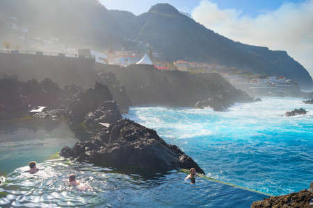 PORTO MONIZ, MADEIRA, PORTUGAL - FEB 03, 2020: People bathes in natural lava ocean pools. Lava pools are the main attraction of Madeira.のeditorial素材