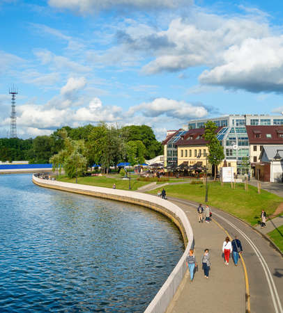 MINSK, BELARUS - JULY 17, 2019: People walking by Svisloch river embankment in bright sunny daytime, green park and city architecture in backgroundのeditorial素材