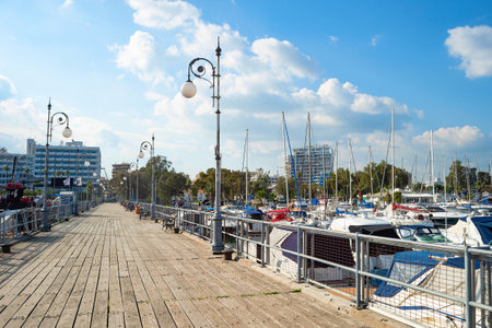 Wooden pier of marina with moored yachts and motorboats, hotels and apartments buildings in bright evening sunshnie, Larnaca, Cyprusの写真素材