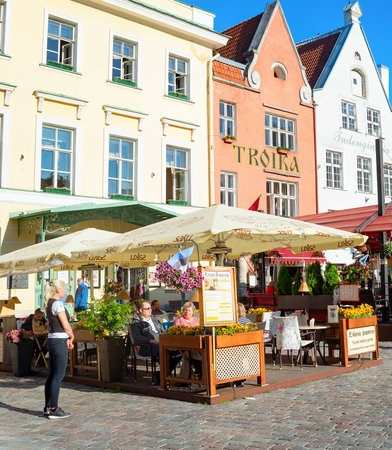 TALLINN, ESTONIA - JULY 14, 2019: People in cafes and restaurants on tourist paved street of old town with houses of traditional architecture in bright sunshine.のeditorial素材