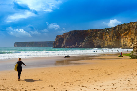 Woman with surfboard on the beach. Moody weather. Algarve, Portugalのeditorial素材