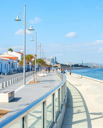 People walking by Larnaca city embankment with typical architecture buildings in white color in bright sunshine, Cyprusの写真素材