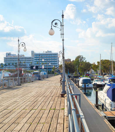 Sunshine view of yachts and motorboats moored by pier in marina, Larnaca cityscape with resort hotels and apartments in background, Cyprusの写真素材
