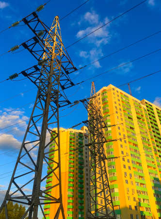Transmission power tower in front of apartment building at sunsetの写真素材