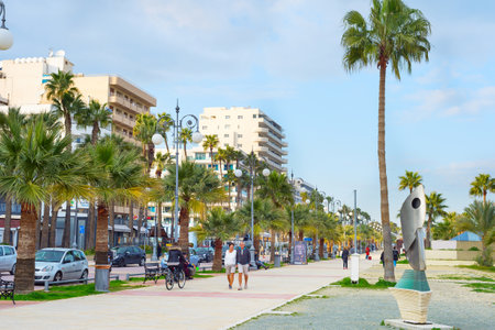 LARNAKA, CYPRUS - FEB 18, 2019: People walking by Larnaca city embankment with typical architecture buildings in bright sunshine day. Cyprusのeditorial素材