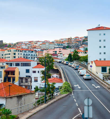 Aerial Funchal cityscape, traffic on hill road, residential houses with red rooftops, Madeira, Portugalの写真素材