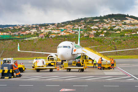 FUNCHAL, MADEIRA, PORTUGAL - FEBRUARY 12, 2020: Ground crew prepare airplane for flight at Cristiano Ronaldo International Airport in Madeira, Portugalのeditorial素材