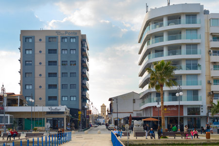 LARNAKA, CYPRUS - FEB 18, 2019: People walking by Larnaca city promenade. Hotel buildins. Saint Lazarus church in the background. Cyprusのeditorial素材