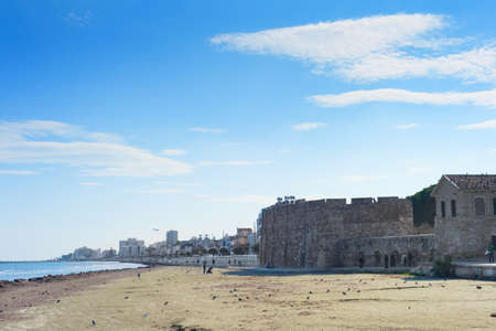 LARNACA, CYPRUS - FEBRUARY 17, 2019: People walking at the resort embankment of Larnaca, Laranaca Castle and fort in the backgroundのeditorial素材