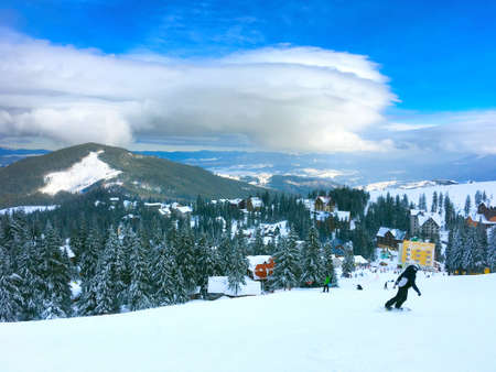 Snowboarders snowboarding on a ski resort mountain slope. Dragobrat, Carpathian Mountains, Ukraineの写真素材