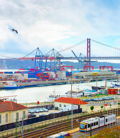 Seagulls over Lisbon commercial port, ships containers and freight cranes, skyline with 25th April Bridge and Tagus river, Portugalのeditorial素材