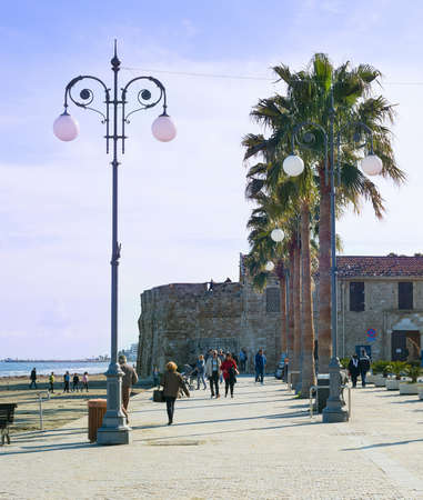 LARNACA, CYPRUS - FEBRUARY 17, 2019: People walking at the resort embankment of Larnaca, Laranaca Castle and fort in the backgroundのeditorial素材