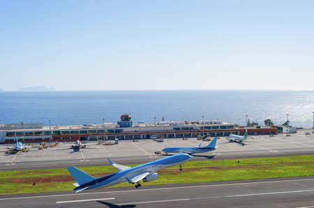 Airplanes taking off at runway of Madeira International Airport, bright sunshine weather, ocean view in background, Funchal, Portugalのeditorial素材