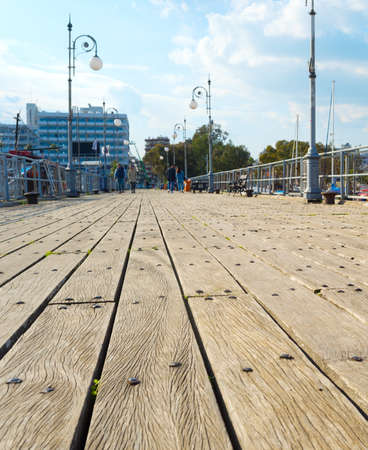 Wooden pier of marina with moored yachts and motorboats, hotels and apartments buildings in the background. Larnaca, Cyprusの写真素材