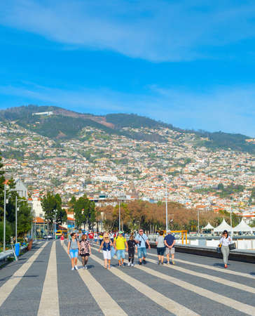 FUNCHAL, MADEIRA ISLAND, PORTUGAL - FEB 04, 2020: Group of people walking by embankment of  Funchal. Funchal is the capital and main sea port of Madeiraのeditorial素材