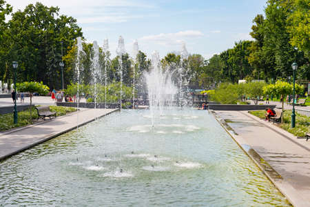 Fountains, central park in summer,walking people in sunshine, benches among green trees, Kharkiv, Ukraineの写真素材