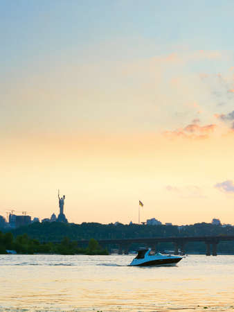 Sunset view of Mother Motherland monument, motor boat on Dnipro river, Paton bridge. Kiev, Ukraineの写真素材