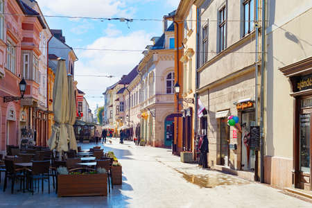 GYOR, HUNGARY - OCTOBER 25, 2021: Touristic street with cafe and shops in sunlight, old architecture, Gyor, Hungaryのeditorial素材