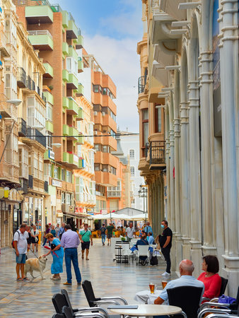CARTAGENA, SPAIN - NOVEMBER 1, 2021: Crowded central shopping city street with cafes, walking people, modern architectureのeditorial素材