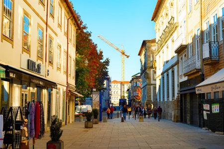 BRAGA, PORTO, PORTUGAL - NOVEMBER 18, 2022: Central touristic street, sunset cityscape, construction crane, shops and cafesのeditorial素材