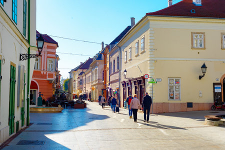 GYOR, HUNGARY - OCTOBER 25, 2021: People walking in central touristic street of the historic old town, colorful architecture in sunshineのeditorial素材