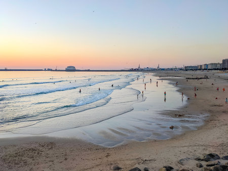 Matosinhos beach at susnet, people relaxing, cityscape and Leixoes port in background, Porto, Portugalの写真素材