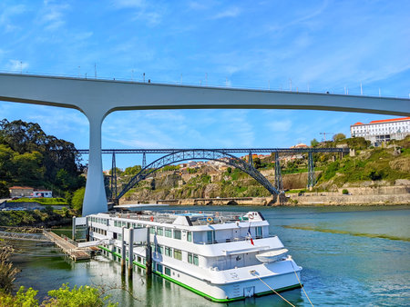 Cruise touristic boat at Douro river in bright sunny day, Sao Jose and Maria Pia bridges in background, ctyscape of Porto, Portugalの写真素材
