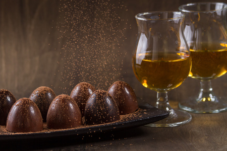 glass of brandy with chocolate on wooden tableの写真素材