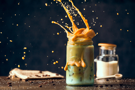 Fresh Cold Iced Coffee Splashing Blue Mason Jar On Wood Table. Copy Space With Selective Focus.の写真素材