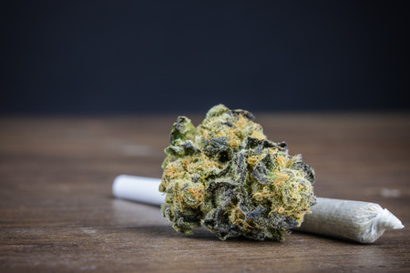 Close Up Of High-Quality Potent Marijuana Bud With Weed Joint On Wood Table With Dark Background. Selective Focus Macro Close Up With Copy Space.の写真素材