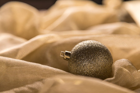 Warm Gold Glitter Sparkle Christmas Bauble On Shiny Holiday Fabric Background. Selective Focus With Copy Space.の写真素材