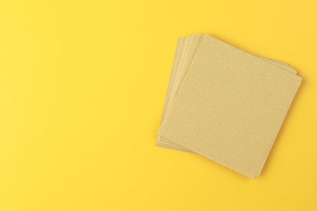 A stack of recycle paper note on yellow background.