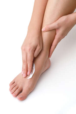 Woman applying moisturiser cream on her leg over white backgroundの写真素材
