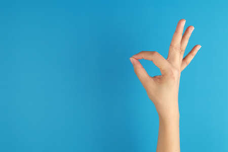 Woman hand pointing okay, yes, accepting hand sign isolated on blue backgroundの写真素材