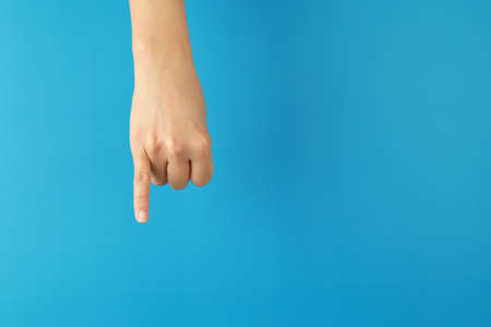 Woman hands showing little finger on blue background, gesture of making a promise.の写真素材