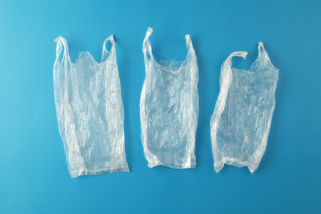 Transparent waste plastic bags on blue background.
