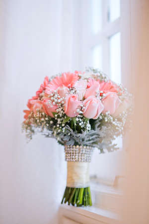 Pink bridal bouquet standing beside window.の写真素材