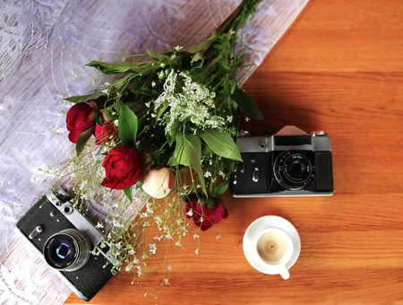 Beautiful Vintage Cameras with a colorful bouquet of flowers and decorative candles on the wooden tableの写真素材