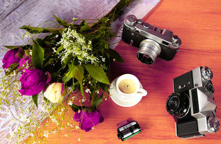 Beautiful Vintage Cameras with a colorful bouquet of flowers and decorative candles on the wooden tablの写真素材