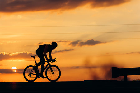Silhouette of strong athlete riding bike outdoors