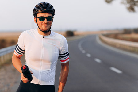Portrait of happy cyclist holding bottle of water outdoorsの写真素材