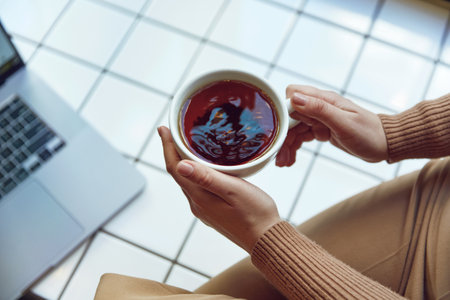 Close up of female hands holding cup with black teaの写真素材