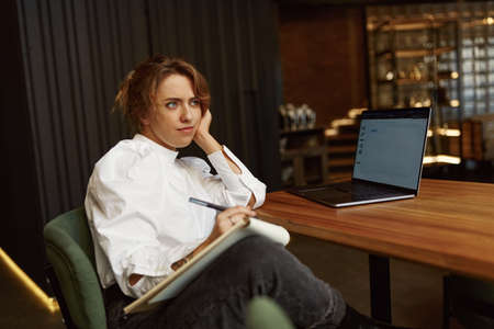 Thoughtful woman sitting at cafe with laptopの写真素材