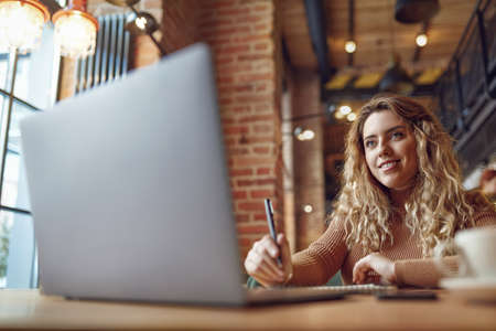 Woman working on laptop and taking notesの写真素材