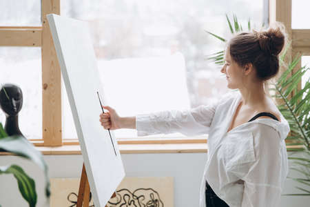 Young woman preparing for painting on easel in studioの写真素材