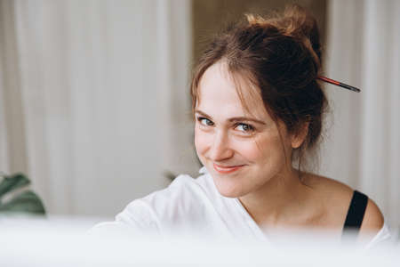 Portrait of talented woman painting on canvasの写真素材