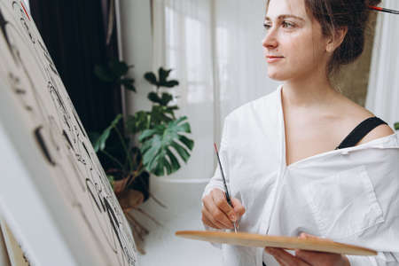 Attractive woman painting with brush on canvasの写真素材