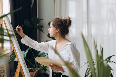 Young woman painting with brush on easelの写真素材