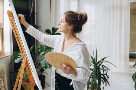 Inspired woman using brush and color palette at workの写真素材